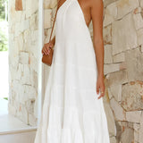 Elegant white halterneck tiered midi dress displayed on a mannequin, showcasing its sleeveless design and flowing tiers ideal for summer resort wear.