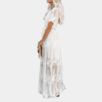 White lace maxi dress with bohemian V-neck design, featuring intricate patterns and a flattering waistline, suitable for a beach wedding.