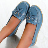 Comfortable casual slip-on white leather tassel loafers for women, shown in light blue color, worn by a person with denim pants.