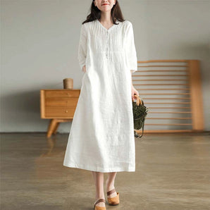 White linen midi dress featuring a V-neckline, pleated details, and long sleeves, designed with sustainability in mind.