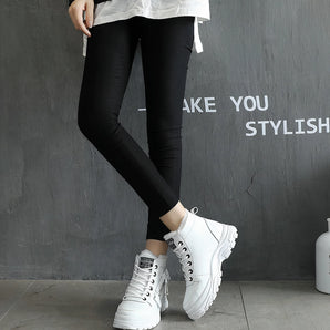 White chunky platform sneakers with trendy lace-up design, showcased on a model wearing casual streetwear.