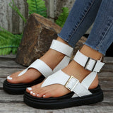 White platform sandals with an adjustable buckle strap and chunky sole, worn with tartan shorts visible.