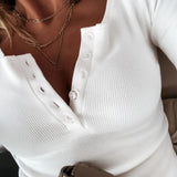 White ribbed Henley blouse with a fitted design, featuring long sleeves, a collar, and a button-up front, styled on a woman's torso.