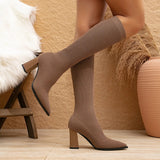 White ribbed high heel sock boots with a block heel, worn on a model's legs showing from the knee down. The boots are stylish and suitable for winter wear, emphasizing comfort and fashion.