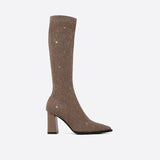 White ribbed high heel sock boots with a stylish winter block heel, featuring a synthetic rubber sole and leather-like texture, worn on a human leg, showcasing a fashionable look suitable for colder seasons.