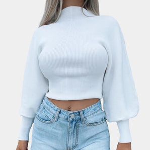White ribbed knit cropped sweater with high neck and bell sleeves, shown in size XL, paired with jeans. The sweater is styled with casual outerwear elements, highlighting the arms and shoulders.
