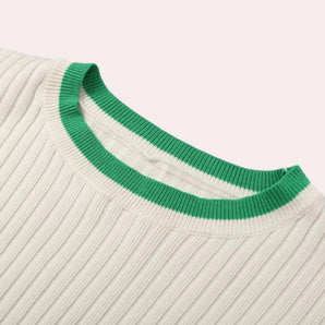 White ribbed knit top with a distinctive green collar, featuring long sleeves and a subtle pattern, designed as a unisex spring sweater.