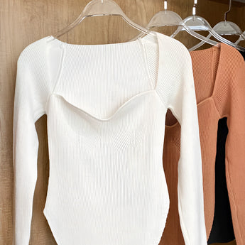 White ribbed scoop neck long sleeve bodysuit on a clothes hanger, showcasing the stylish neckline and sleeve design against a neutral background.