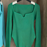 Green ribbed scoop neck long sleeve bodysuit in XL size hanging on a clothes hanger, showcasing women's fashion top with a jersey fabric pattern.