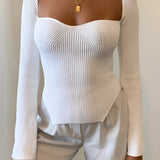 A woman wearing a white ribbed scoop neck long sleeve bodysuit, showcasing the fit and design on the upper body, emphasizing the neckline and sleeves.