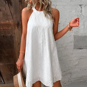 White sleeveless eyelet halter dress, knee-length, suitable for casual and beachwear occasions, displayed on a standing mannequin or model.