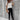 Elegant women's summer office wear featuring a white V-neck short sleeve blouse, styled with complementary accessories such as sunglasses and a hat, paired with trousers and footwear.