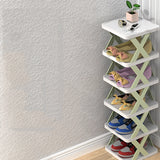 Modern minimalist white X-shaped corner bookshelf made of wood, featuring multiple shelves for storage. The bookshelf is placed in a room with hardwood flooring and includes decorative elements such as flowerpots.