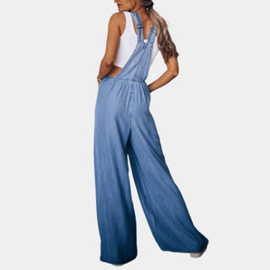 Wide-leg backless sleeveless blue jean jumpsuit for women displayed on a mannequin, showcasing its fashion-forward design with a fitted waist and flowing legs.