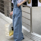 Woman wearing wide-leg vintage denim overalls with adjustable shoulder straps, showcasing a trendy casual chic jumpsuit style.