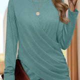
Woman wearing a blue asymmetrical long sleeve wrap tunic top, styled for fall fashion, featuring a v-neckline, with her hand resting on her hip and her hair down.