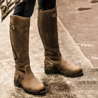 Brown knee-high winter riding boots made of insulated waterproof leather, shown on a human leg.