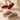 
A pair of winter slip-on shoes in white with pink and red accents, featuring a fleece lining, insulated and waterproof design, suitable for walking and fashion.