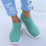 Women's aqua green lightweight slip-on breathable sneakers worn on a person's feet, showcasing a sleek design with azure accents against a white background.