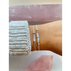 A woman's wrist adorned with minimalist gold beaded bracelets, showcasing dainty layered jewelry.