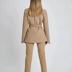 Women's beige belted blazer featuring a tailored fit with structured shoulders, a classic collar, and long sleeves. The jacket accentuates the waist for a flattering silhouette.