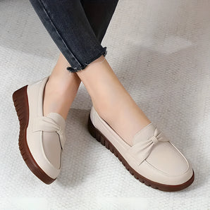 Beige women's loafers with a bow-tie detail, designed for comfort and easy slip-on wear.