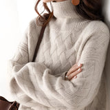 A woman wearing an oversized chunky knit turtleneck sweater in beige, with long sleeves and a relaxed fit, perfect for winter fashion. The sweater appears cozy, with its thick texture, and the turtleneck adds warmth and style.
