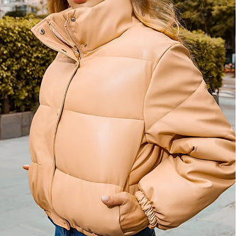 Women's beige cropped puffer jacket featuring a high collar and insulated design, styled for winter with long sleeves and a fashionable, waist-length cut.