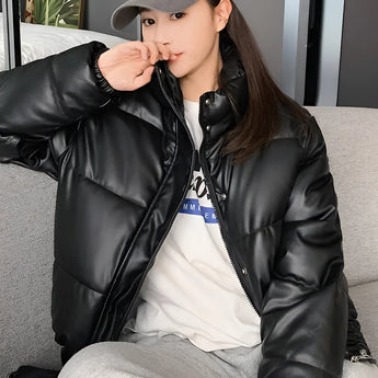 Women's beige cropped puffer jacket with a high collar and long sleeves, designed for winter insulation. The jacket is highlighted in flash photography, showcasing its stylish and cool outerwear appeal.