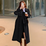 Women's beige double-breasted long trench coat with a stylish collar and long sleeves, designed for chic autumn wear, displayed on a model in a formal setting.
