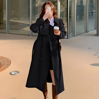 Women's beige double-breasted long trench coat with a stylish collar and long sleeves, designed for chic autumn wear, displayed on a model in a formal setting.