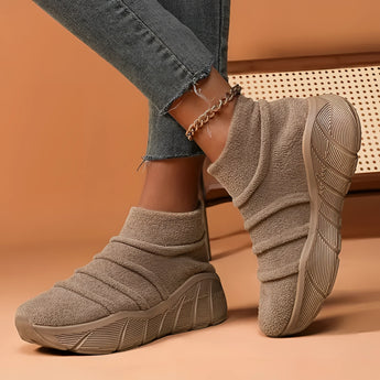 Women's beige high-top sock sneakers shown on a person, styled with jeans. The sneakers are designed for lightweight ergonomic comfort.