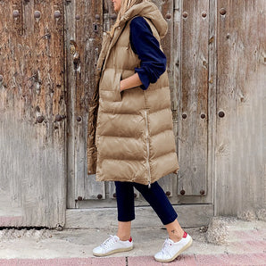 Beige hooded puffer vest for women, featuring a stylish sleeveless design suitable for winter, paired with denim pants.