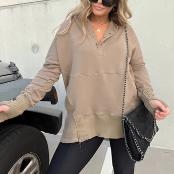 A woman wearing a light brown, XXL casual buttoned pullover hoodie with ribbed cuffs, standing outdoors.