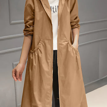 Women's beige lightweight hooded trench coat in a waterproof material, designed as a spring jacket. The coat features a collar, long sleeves, and falls to knee length. It is styled for the Brown / 4XL variant, with a flattering waist design suitable for a fashionable, casual look. The model showcases the coat in an outdoor setting.
