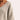 Women's beige oversized V-neck sweater on a mannequin, showcasing the knitwear's wide neckline and loose fit, perfect for a cozy fall look. The sweater covers the shoulders and arms, emphasizing its comfortable and relaxed style.