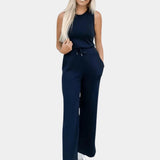 Model wearing a sleeveless beige jumpsuit, showcasing a casual summer outfit with a fitted waist, designed for a comfortable and stylish look.