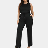 A woman wearing a black sleeveless jumpsuit, featuring a fitted waist and wide-leg trousers, suitable for a casual summer outing.