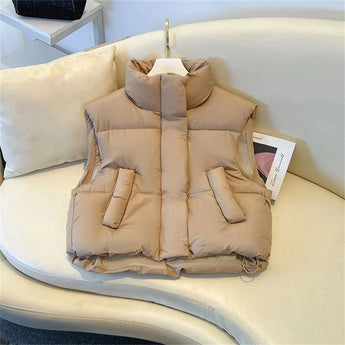 Beige sleeveless puffer vest for women, shown in a lightweight, insulated design suitable for winter; displayed on a chair, with a focus on comfort and fashion.