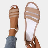 Women's beige strappy flat sandals featuring a pearl ankle bracelet, shown on a person's foot.