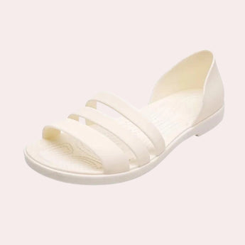 Women's beige strappy flat sandals with pearl ankle bracelet, featuring a simplistic and elegant design, suitable for casual or dressy occasions.