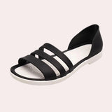 Women's beige flat sandals with strappy design and pearl ankle bracelet.