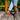 Women's black casual sneakers with a stylish contrast sole, worn by a person standing on grass. The sneakers are paired with brown attire, showcasing a fashionable look suitable for walking.