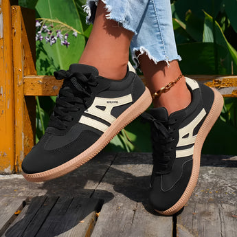 Women's black casual sneakers with a stylish contrast sole, designed for walking. The sneakers are paired with denim jeans, ideal for a casual and sporty outdoor look.