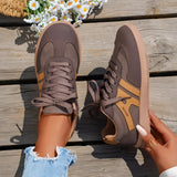 Women's black casual sneakers with a stylish contrast sole, shown on a person's foot, with an outdoor setting featuring some greenery and flowers in the background.
