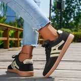Women's black casual sneakers with a stylish contrast sole, worn with jeans.