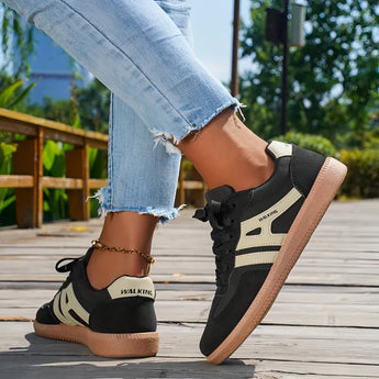 Women's black casual sneakers with a stylish contrast sole, worn with jeans.