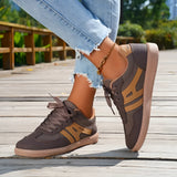 Women's black casual sneakers with a stylish contrast sole, shown worn with jeans.