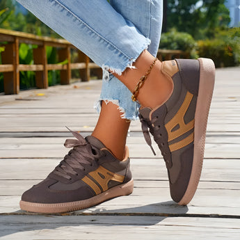 Women's black casual sneakers with a stylish contrast sole, shown worn with jeans.