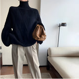 Women's black chunky knit oversized turtleneck sweater featuring long sleeves and a cozy fit, perfect for winter fashion.